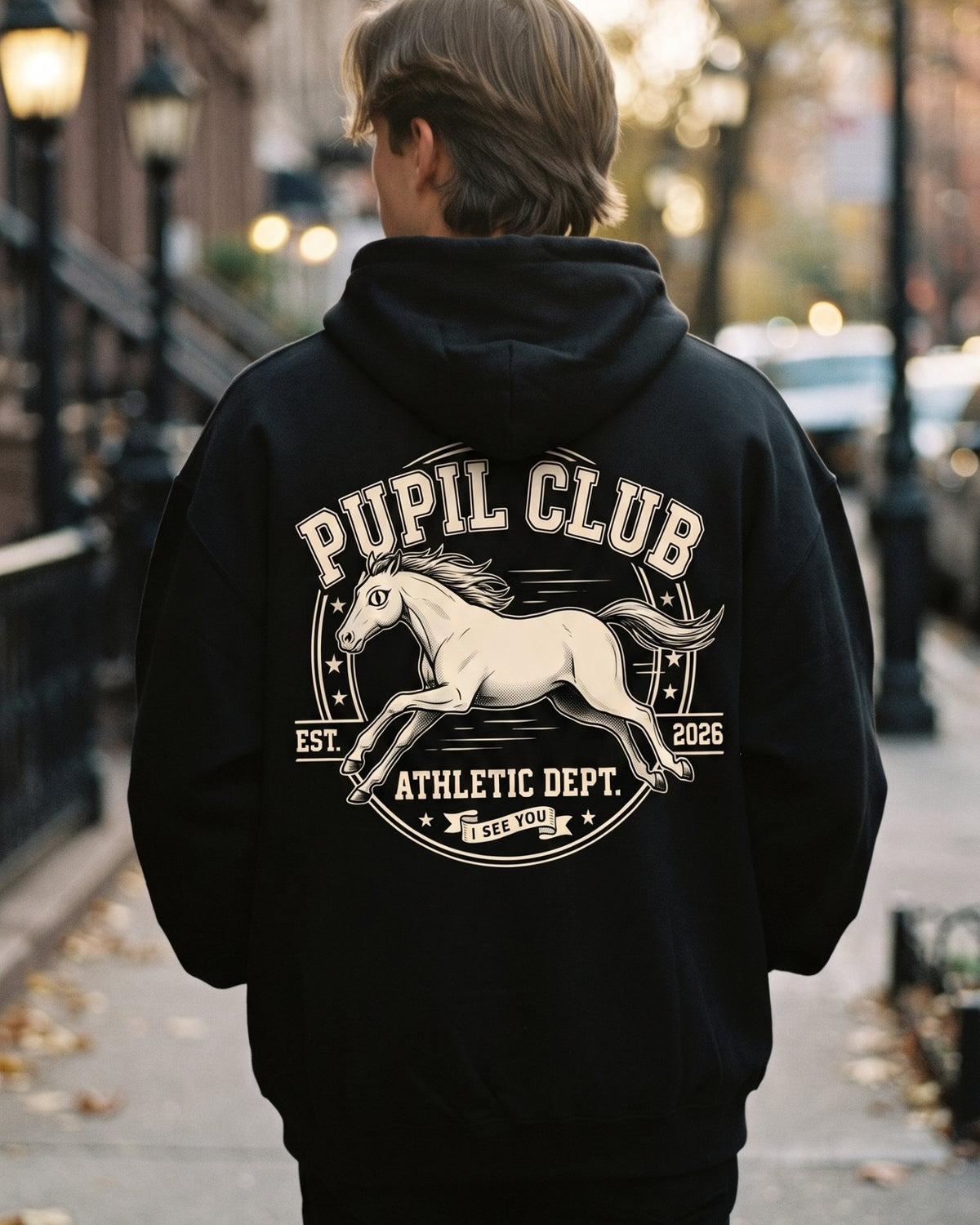 Pupil Club Athletic Dept. Hoodie, back crest, worn on a city street